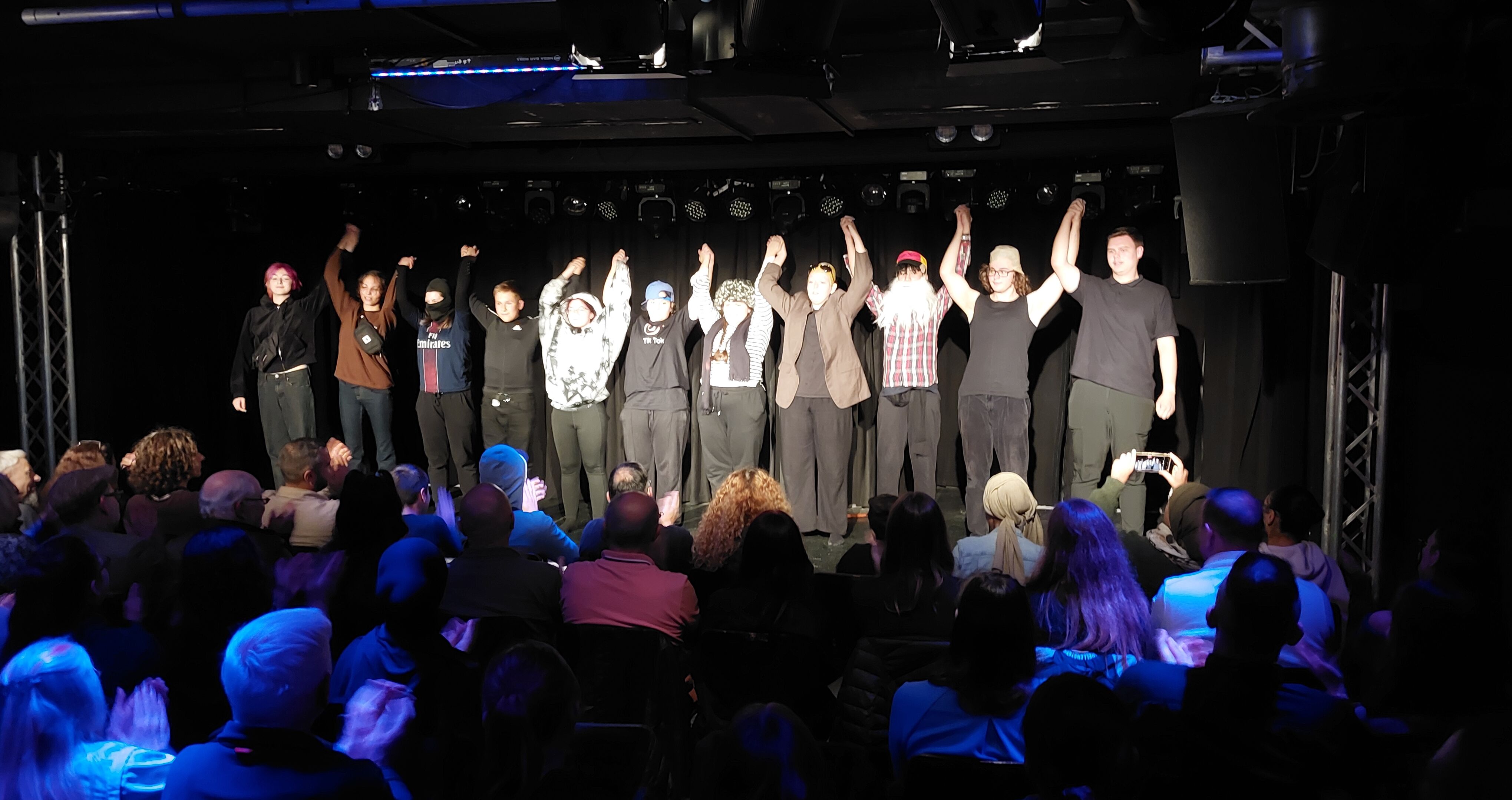 Eine Gruppe von Schüler*innen verbeugt sich auf einer Bühne.