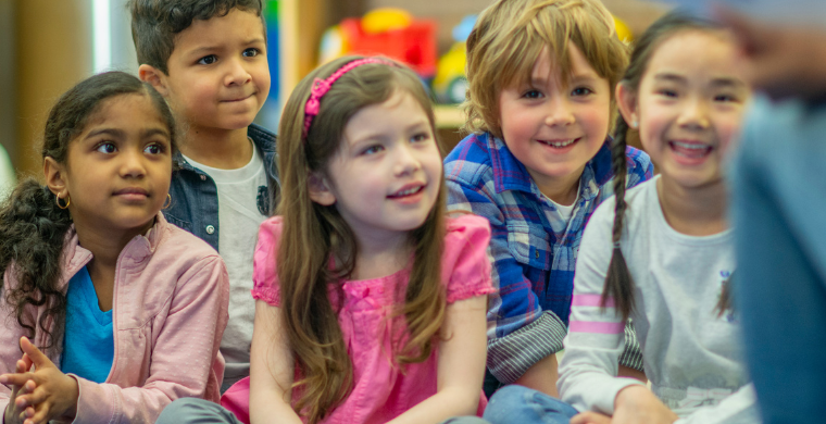 Kindergartenkinder sitzen zusammen auf dem Boden.