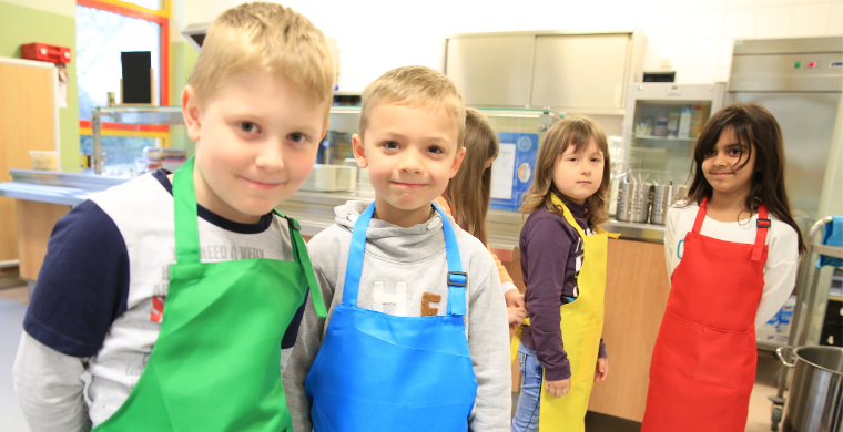 Grundschulkinder stehen in der Schulküche.