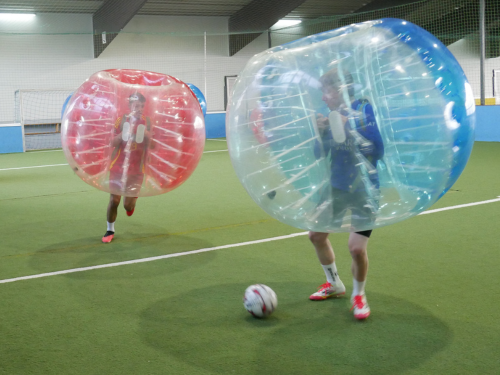 Jugendliche stehen in überdimensionalen Ball-Kostümen auf einem Fußballplatz.