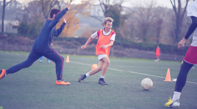 Drei Jugendliche nehmen an einem Herbsttag bei einem Fußballtraining teil.