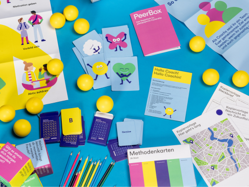 Buntes Spielmaterial liegt auf dem Boden verteilt.