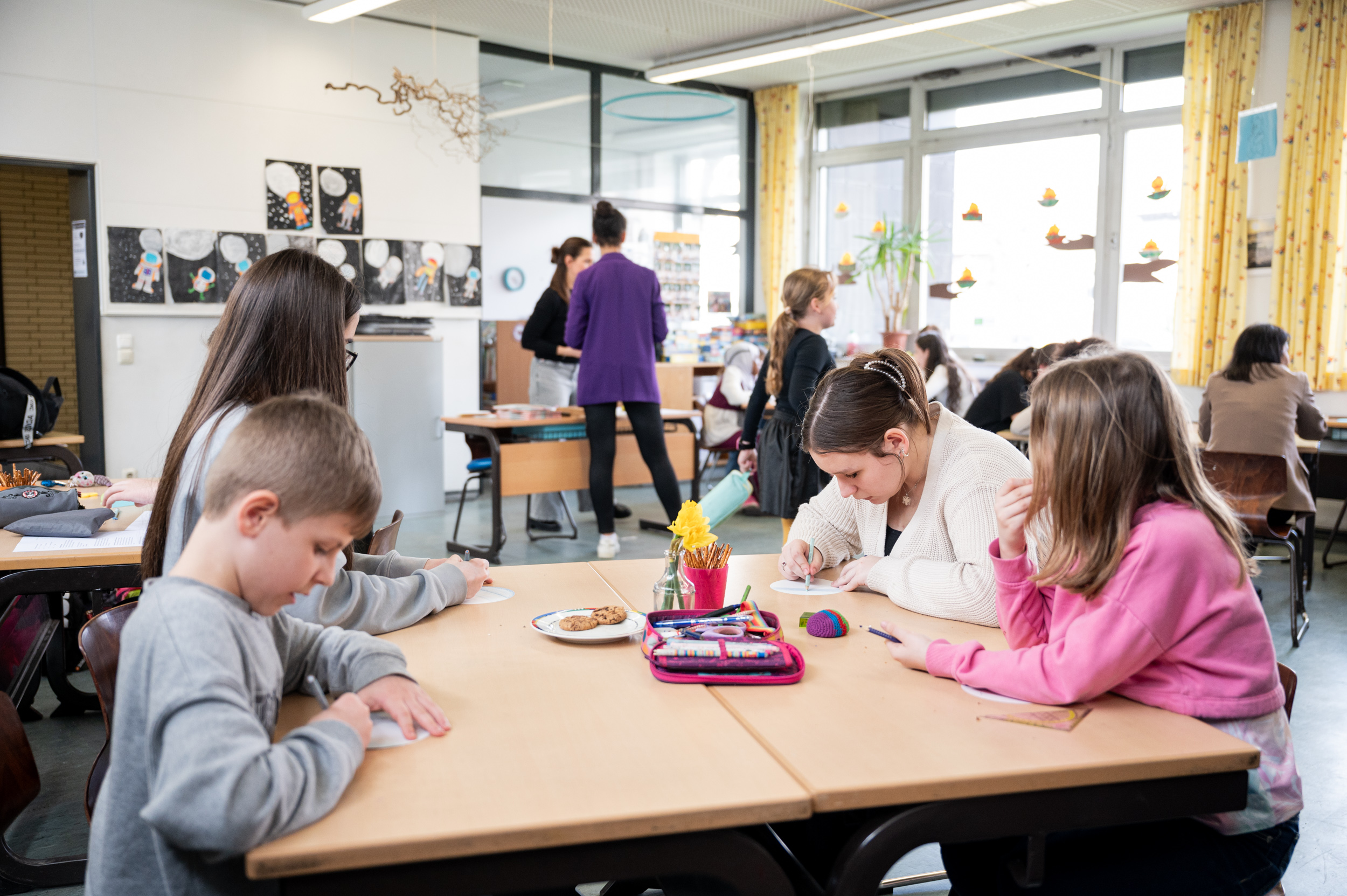 Ältere und jüngere Schülerinnen und Schüler arbeiten im Klassenzimmer zusammen.